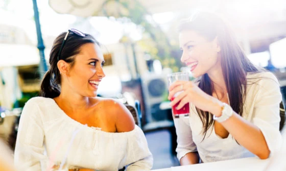Two young attractive women having fun whilst outside having a drink
