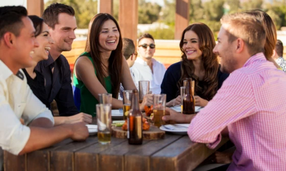 Group of young adults chatting over drinks in a beer garden on a sunny day