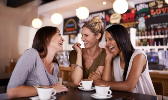 Group of young women laughing whilst out for coffee